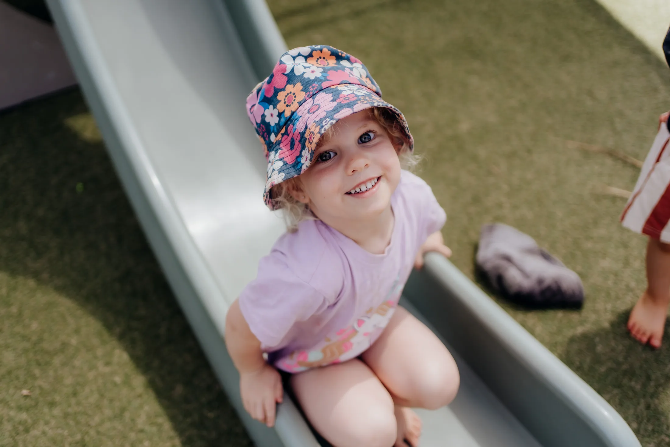 A smiling Tiny Legends child playing on the slide